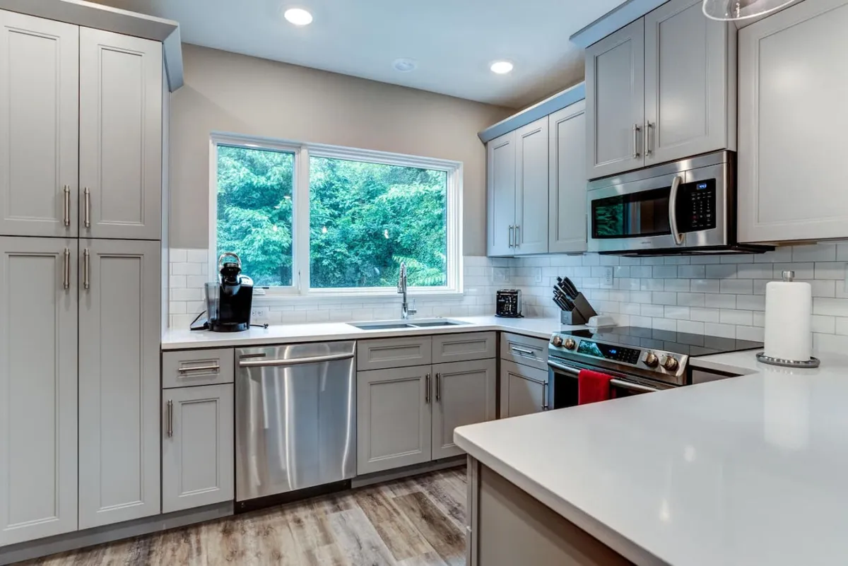 Bright kitchen featuring stainless steel appliances, a kitchen island, and a large window overlooking greenery. The space is designed for both casual mornings and lively gatherings, blending modern functionality with inviting warmth.