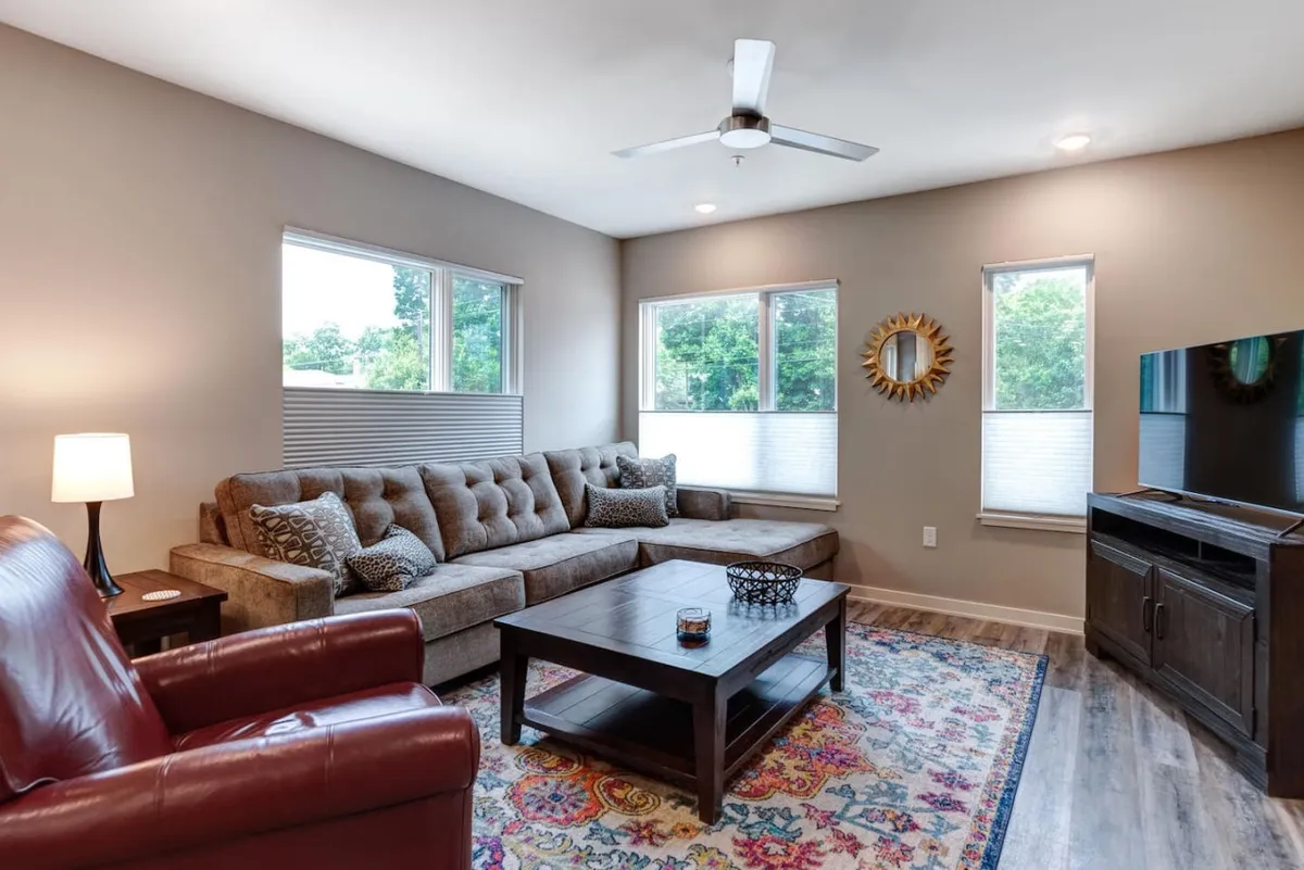 This comfortable living room scene highlights a plush sofa, coffee table, and a television set against a backdrop of large windows. The light-filled setting creates a relaxing atmosphere ideal for unwinding after a day exploring the city.
